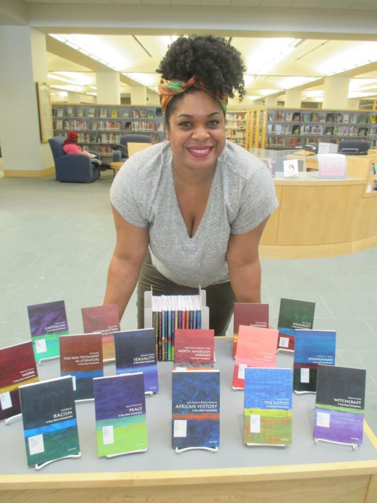 woman hovering over a table of books
