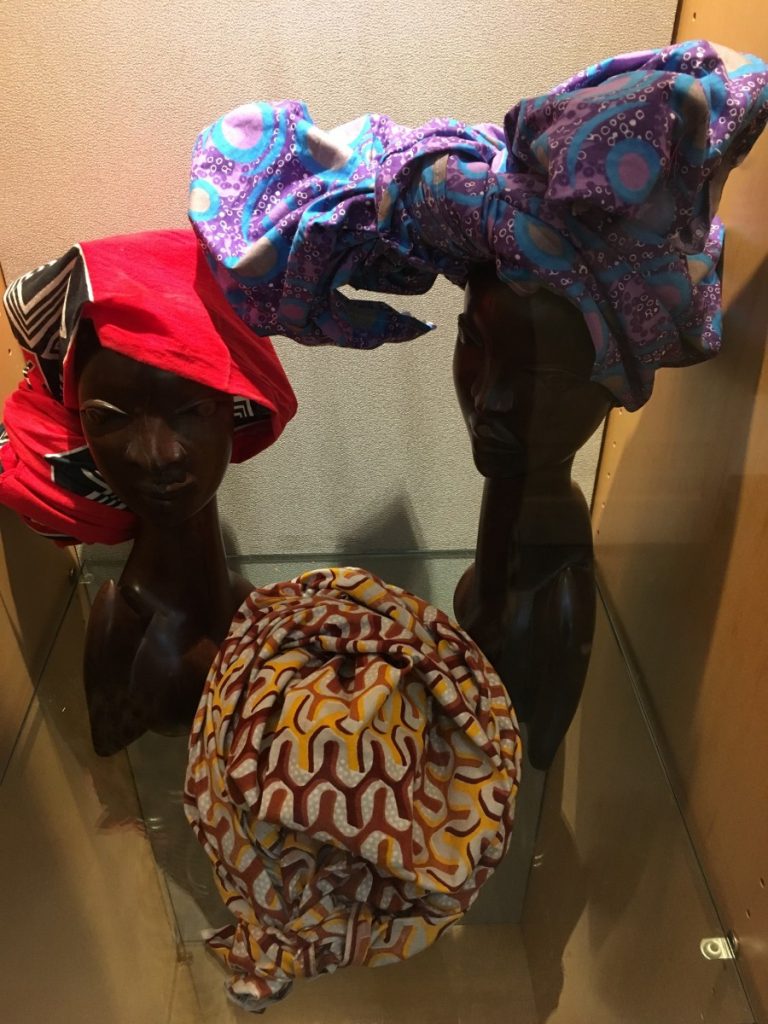 Two wooden busts adorned with colorful head wraps