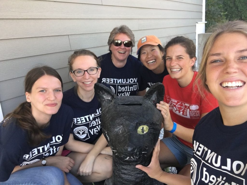 Six volunteers pose with a panther statue.