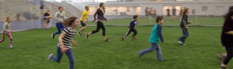 Children playing indoor soccer in a field.