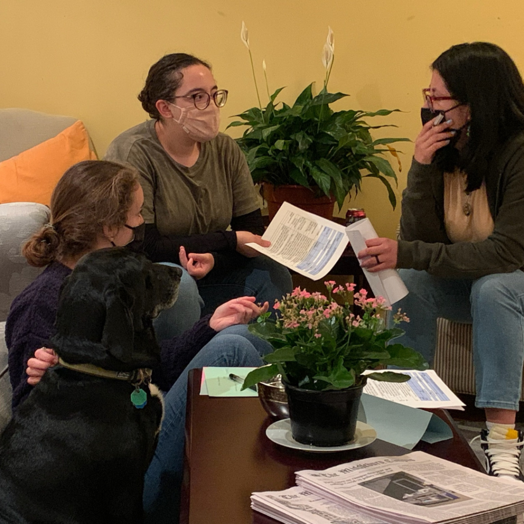 Three Juntos board members in a meeting at the CCE with a CCE advisor's dog, Flash.