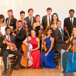 Multiple musicians of color in formal wear holding stringed instruments