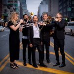 Four Brass musicians and a vocalist in formal wear in the middle of a NYC street
